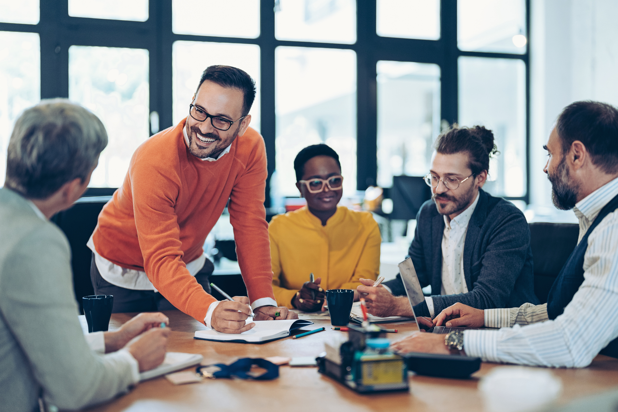 Relaxed, happy leader explaining his concept during a meeting. Multiracial group of business people sitting around a table.