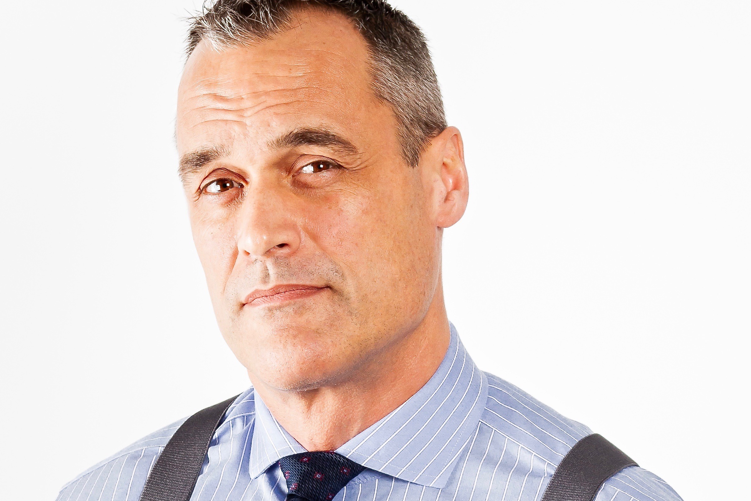 A portrait of Dan Gardner, a white man with a collared striped shirt.