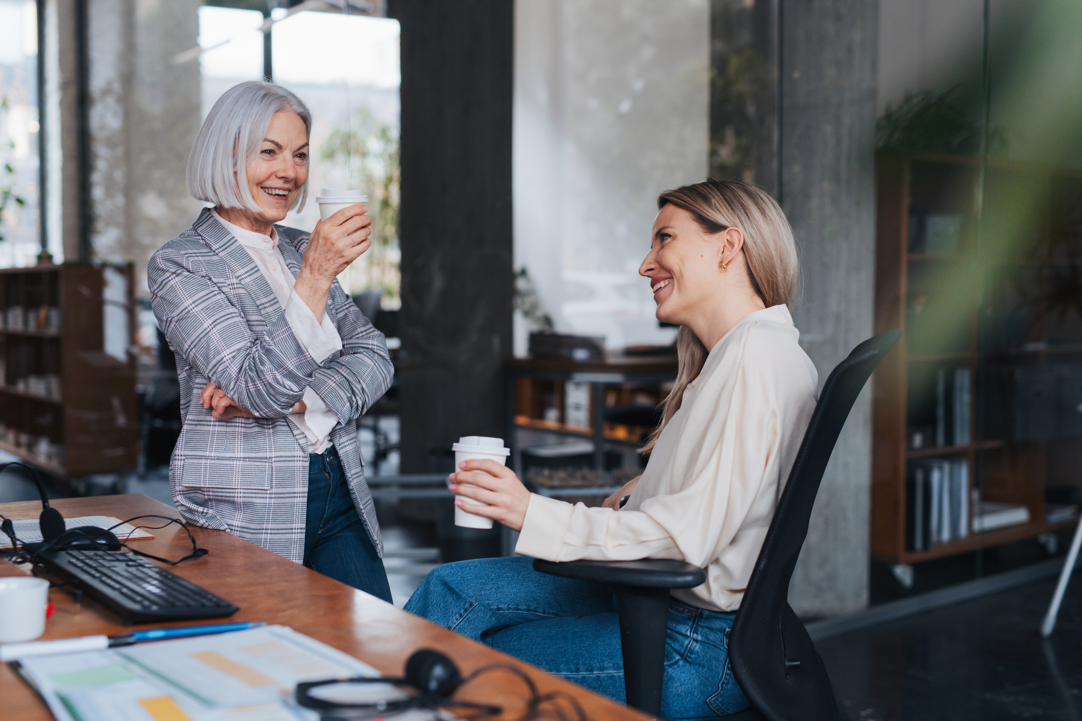 Two women enjoy coffee in an office, representing a servant leader checking in with a team member