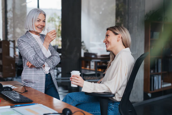 Two women enjoy coffee in an office, representing a servant leader checking in with a team member
