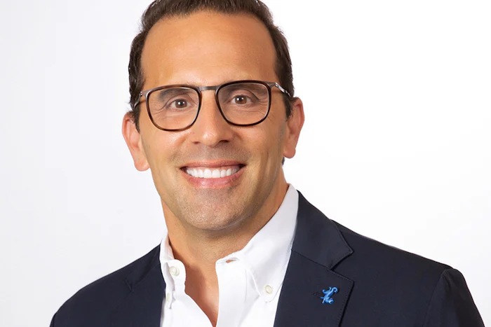 A partial face and shoulders portrait of André Martin, wearing glasses.