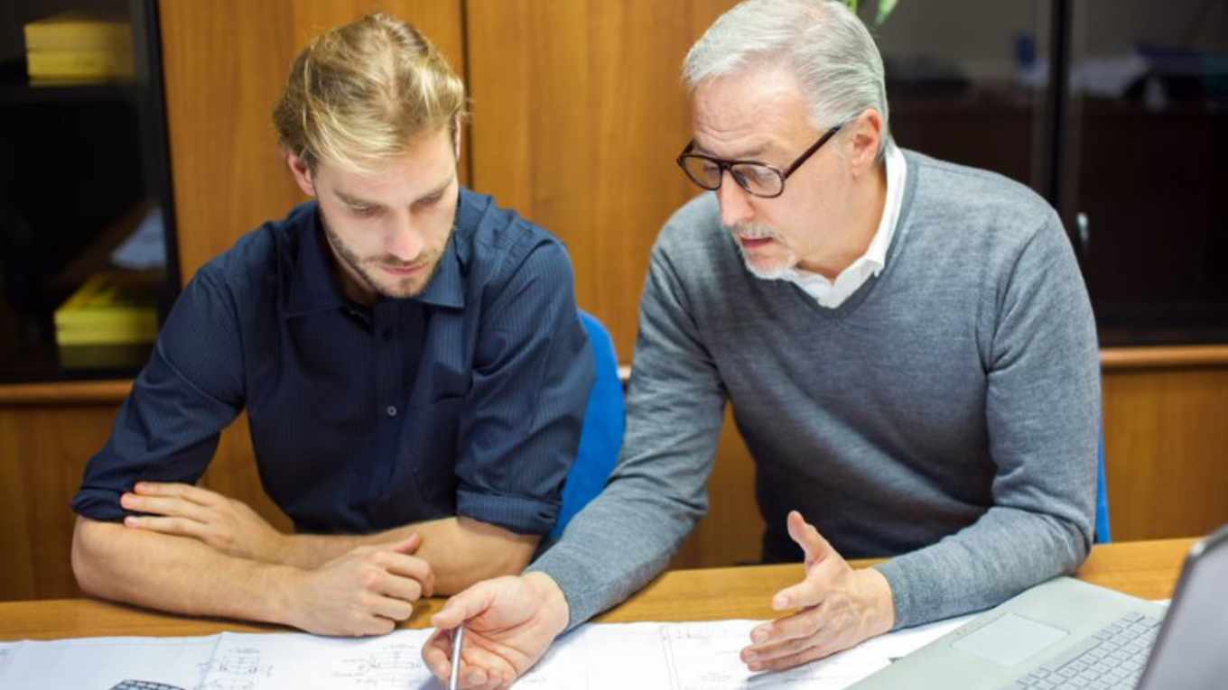 Two male colleagues of different generations discuss work.