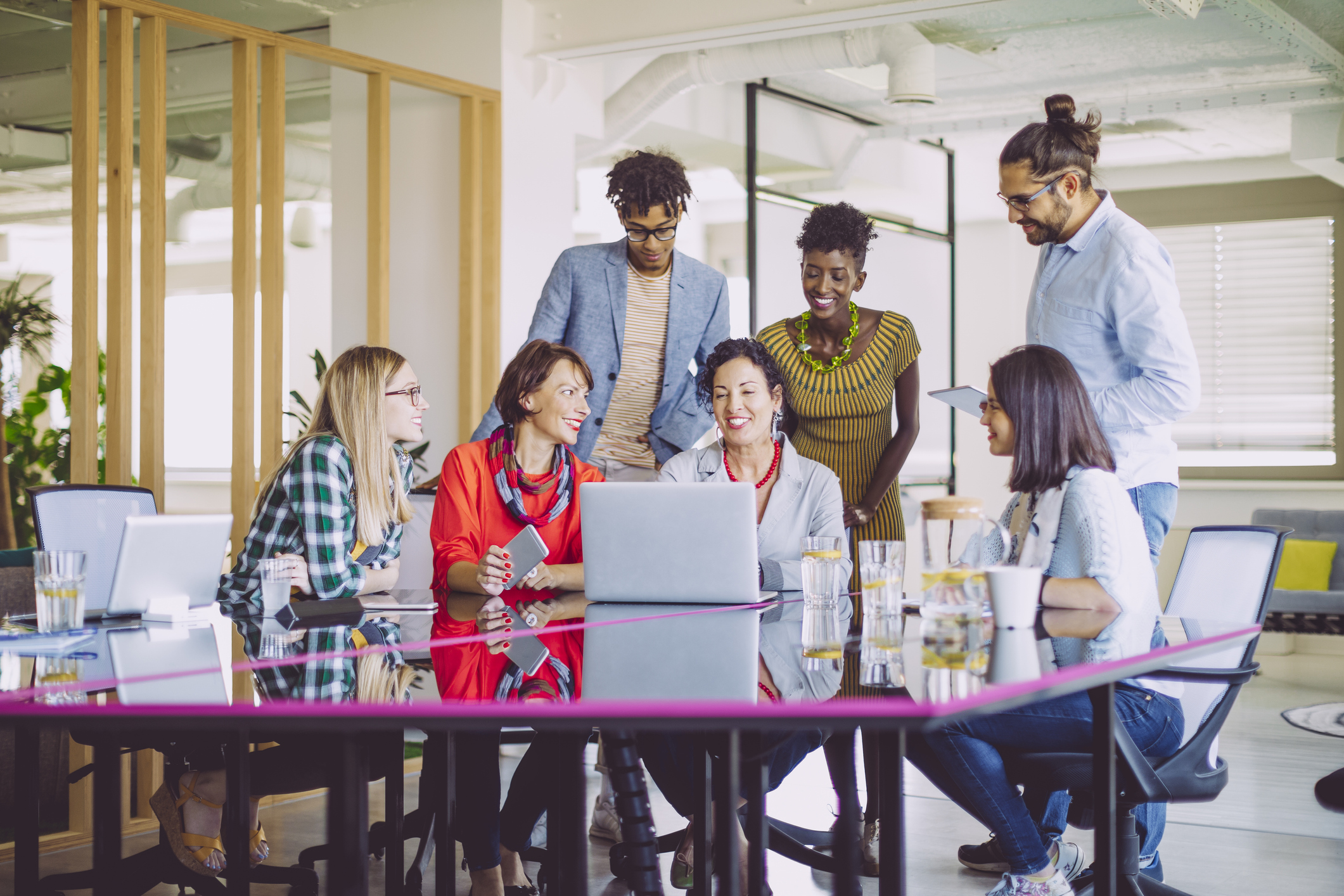 Multigeneration and diverse business team working together in front of shared computer, representing learning about AI together.
