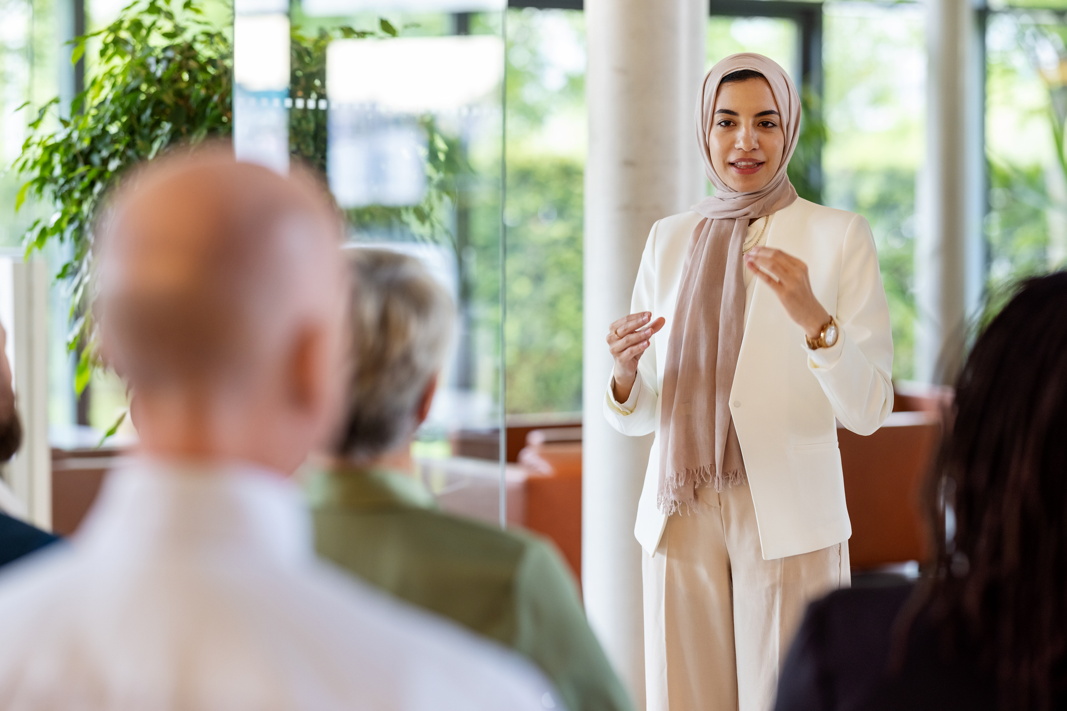 Young middle eastern businesswoman giving a speech in a business seminar. Muslim woman wearing headscarf addressing the audience in a business conference.