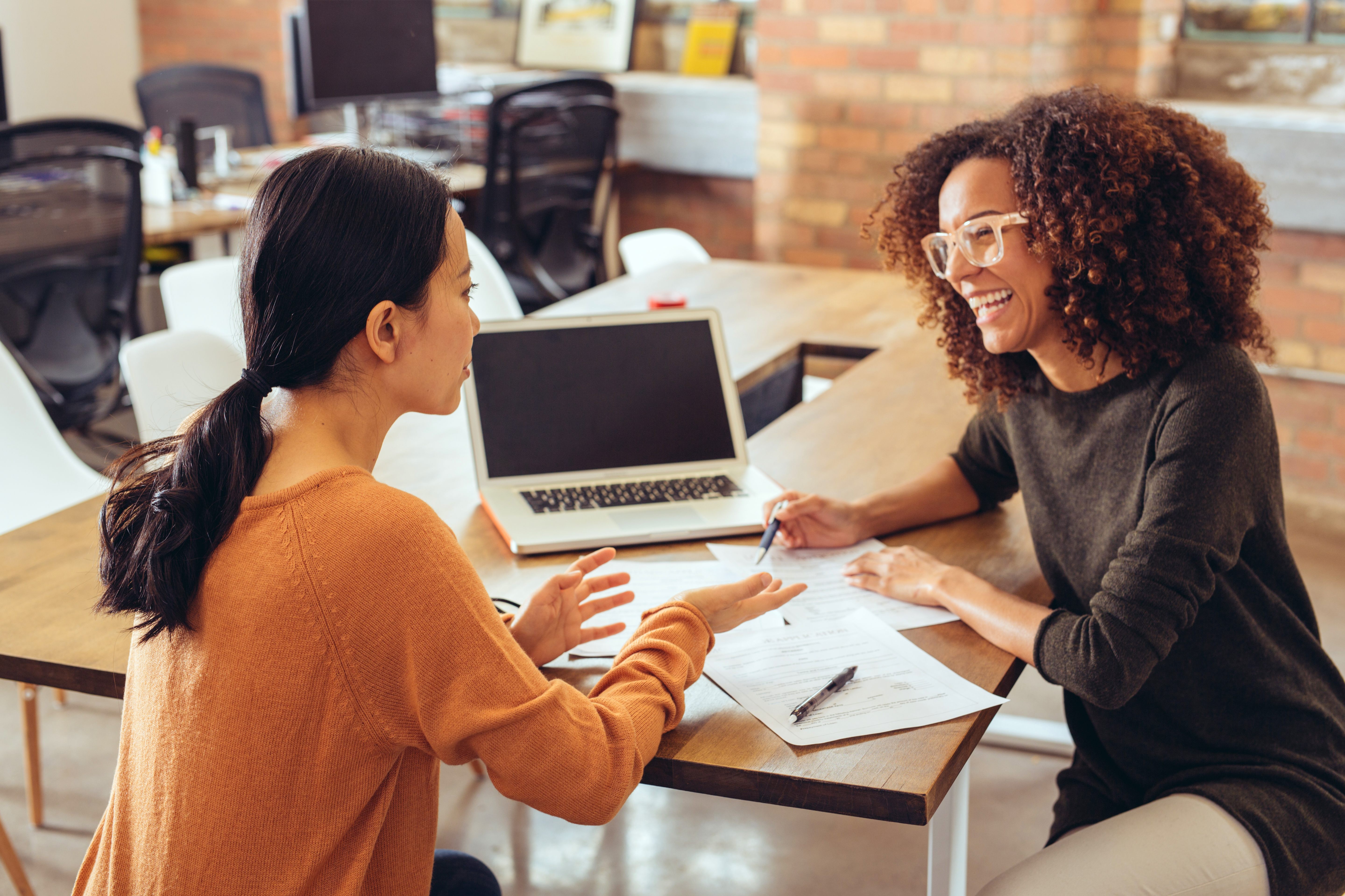 Two female colleagues discussing something in a work environment, representing feedback