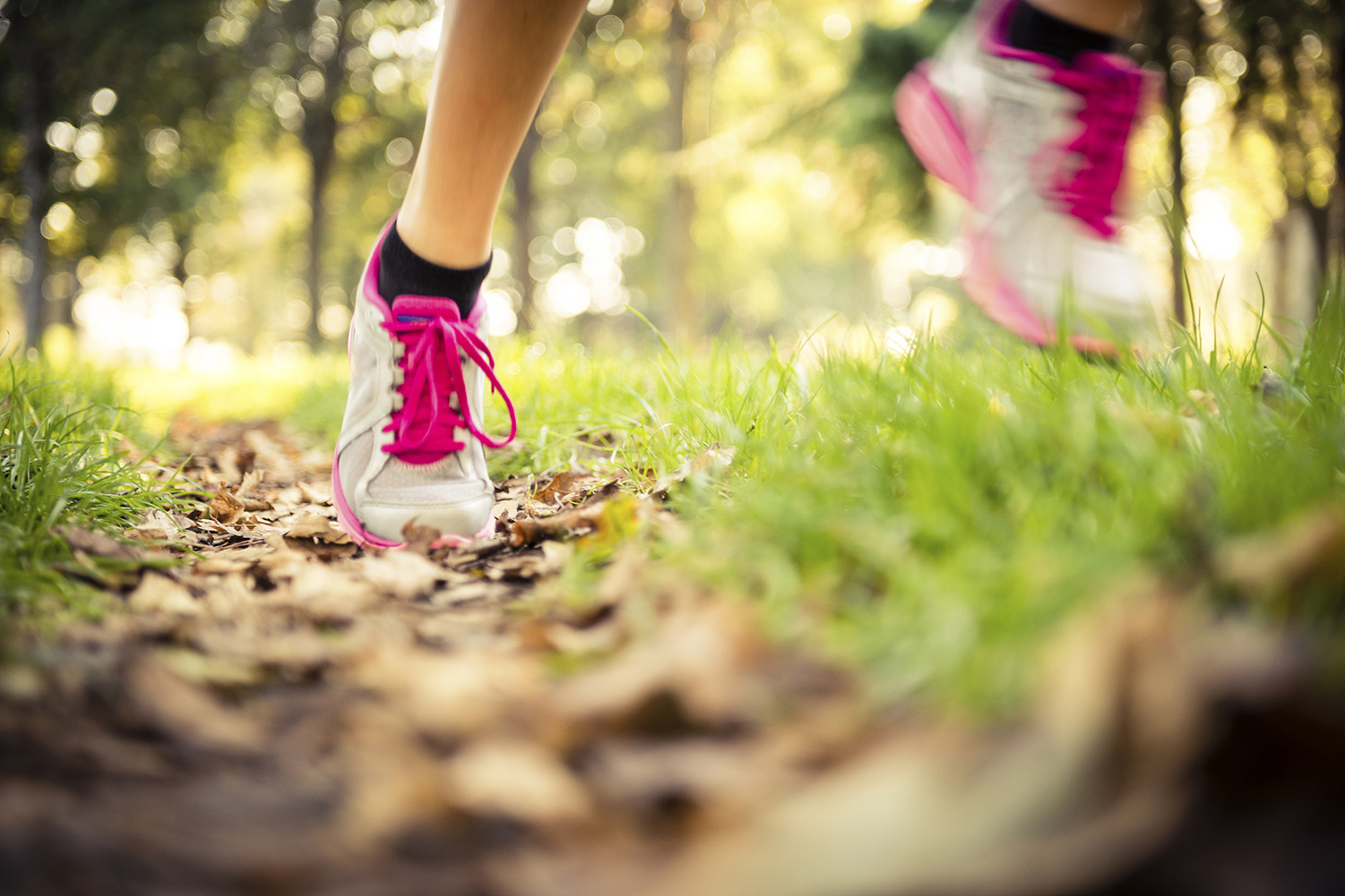 Runner's feet in motion showing grey trainers with pink laces