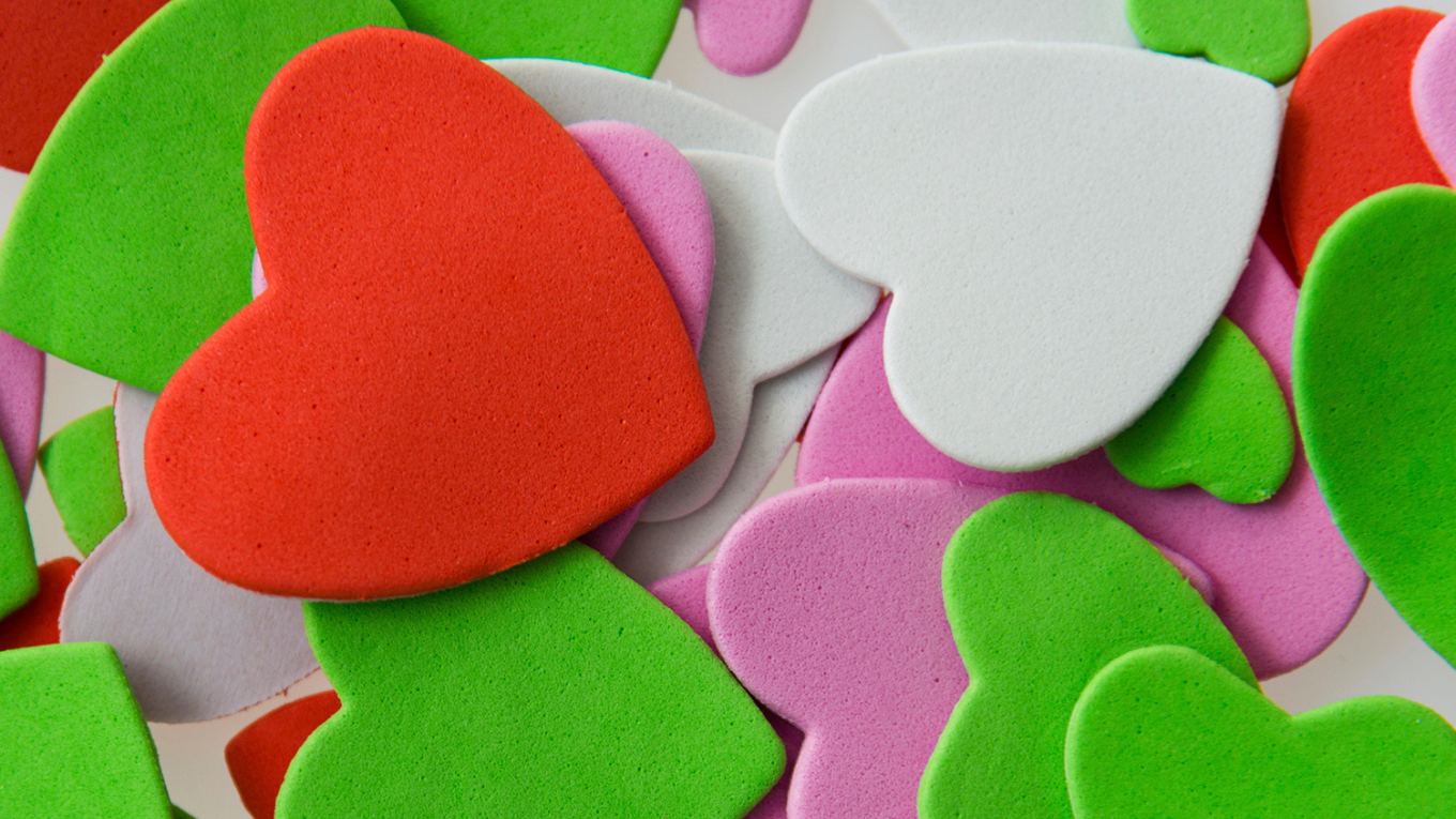 Colorful paper hearts overlap one another.