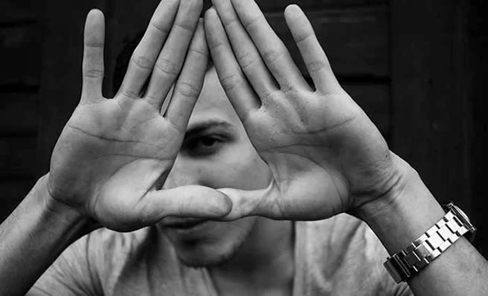 Human holds hands in triangle in front of face