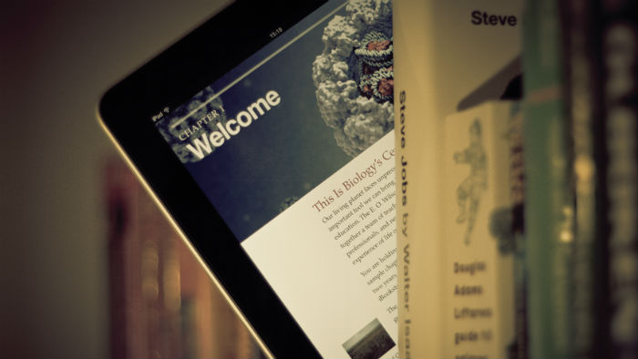 iPad screen with business story hanging out of a bookshelf