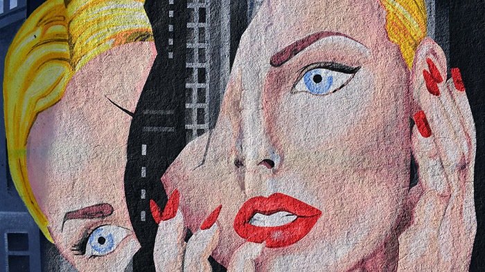 A mural painting of a woman with her hands touching her face.