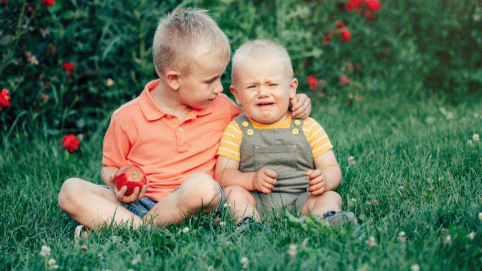 Two young boys sitting in a garden.