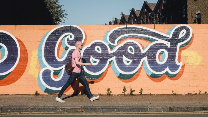 Person walking past "Good" street art
