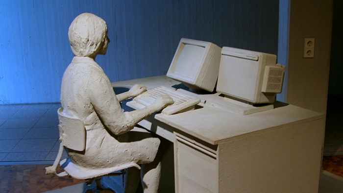 Clay sculpture of human at computer desk