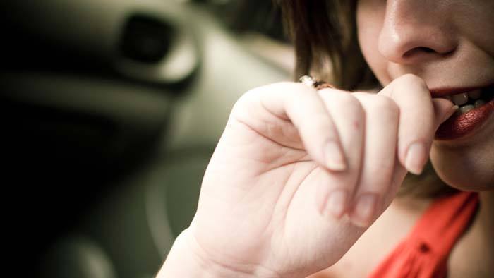 A woman biting her nails.