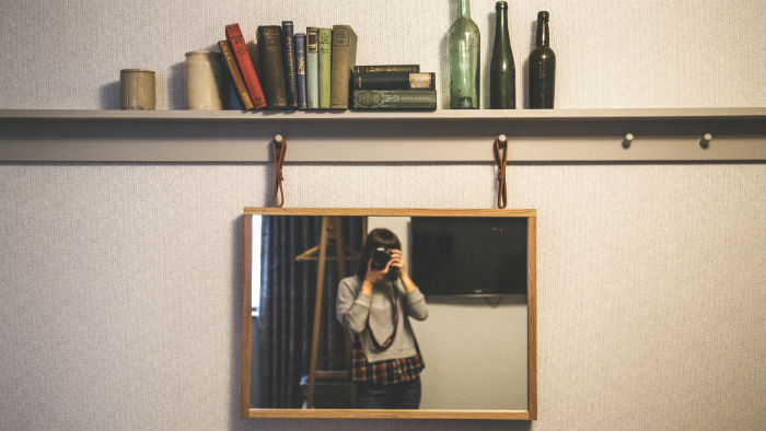 A woman taking a photo of herself in the mirror using a camera. 