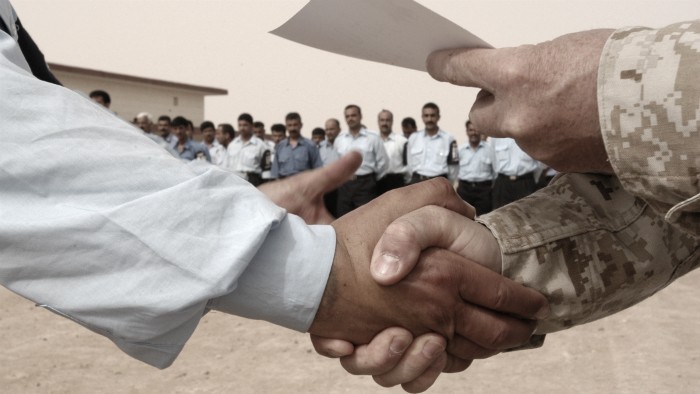 Two people shaking hands in front of a crowd. 