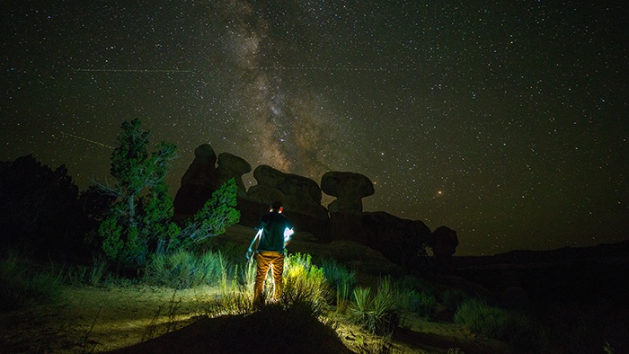 Person standing near rock formation at night
